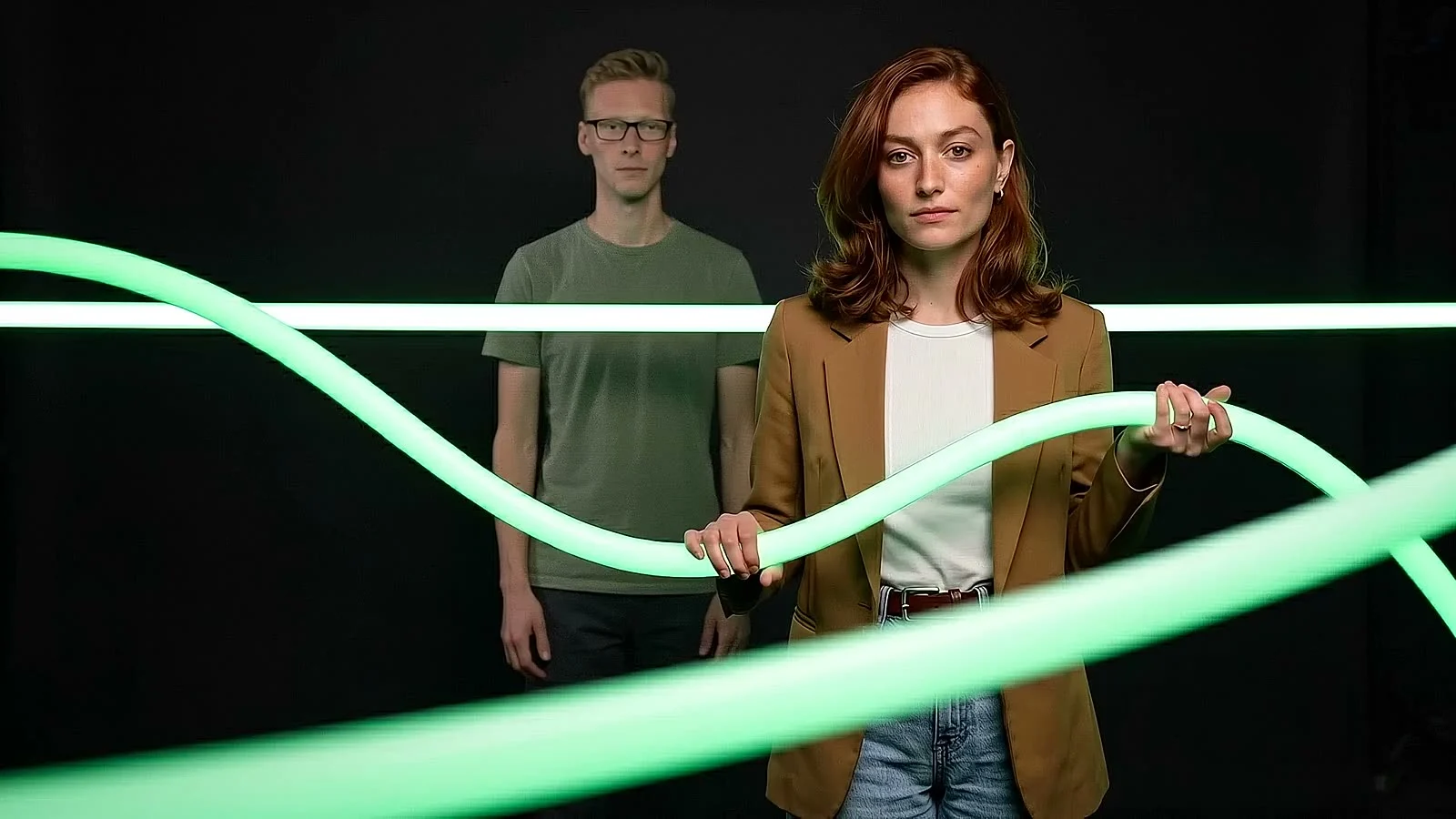Twee collega's houden samen een lichtgevende groene buis vast.