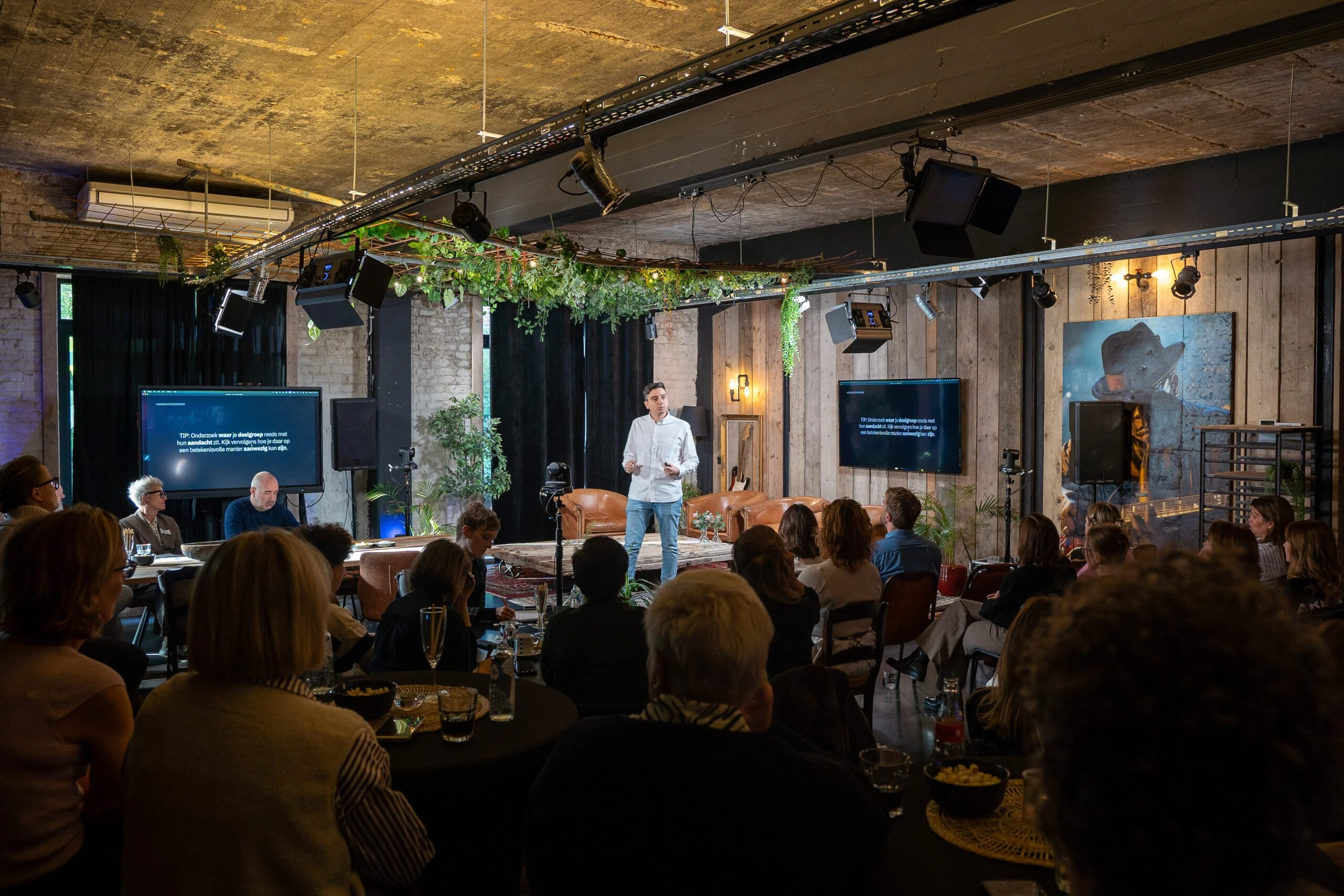 Keynote op de JDI-inspiratiedag in de loft, het publiek zit aan tafels.