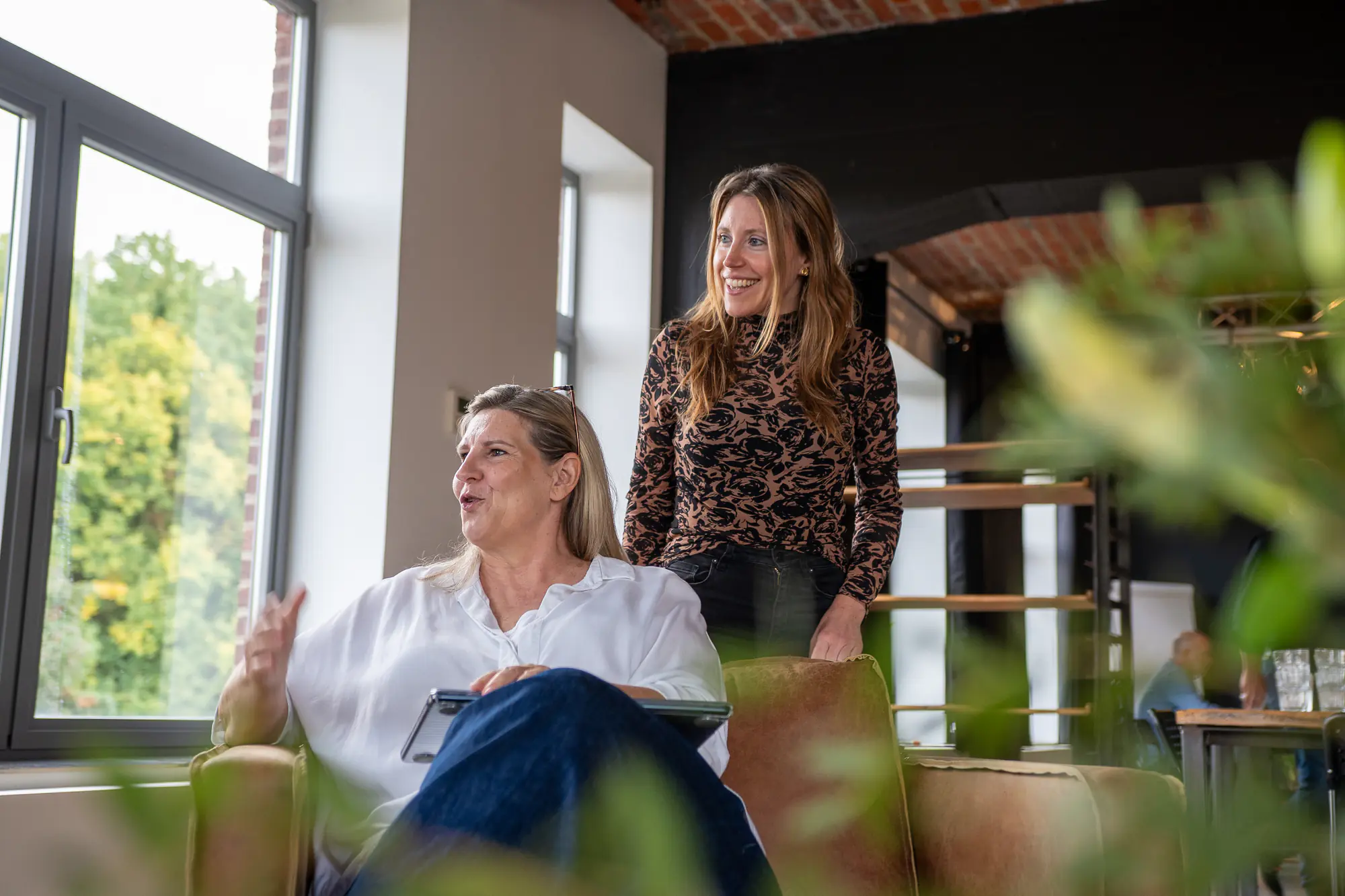 Twee collega's in gesprek bij het raam.
