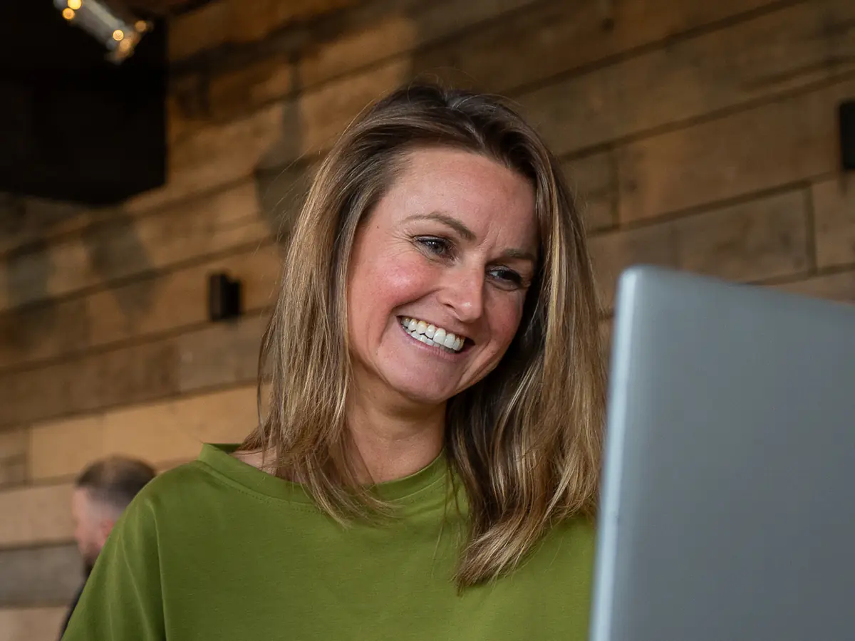 Een collega lacht terwijl ze op haar laptop werkt.