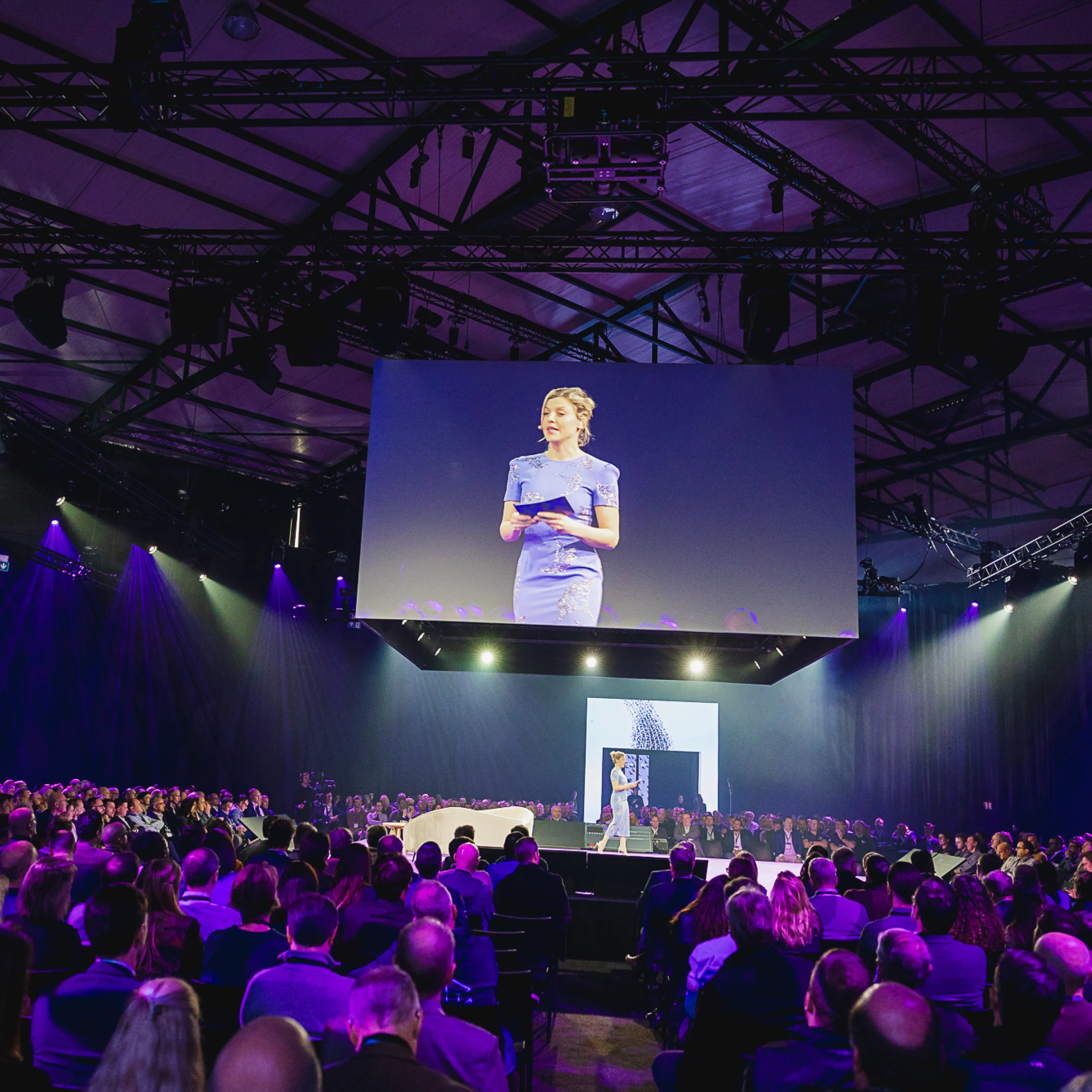 Een spreekster op het podium van Think NXT voor een volle zaal.